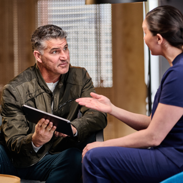An Aspen Dental doctor sits and speaks with a patient. 