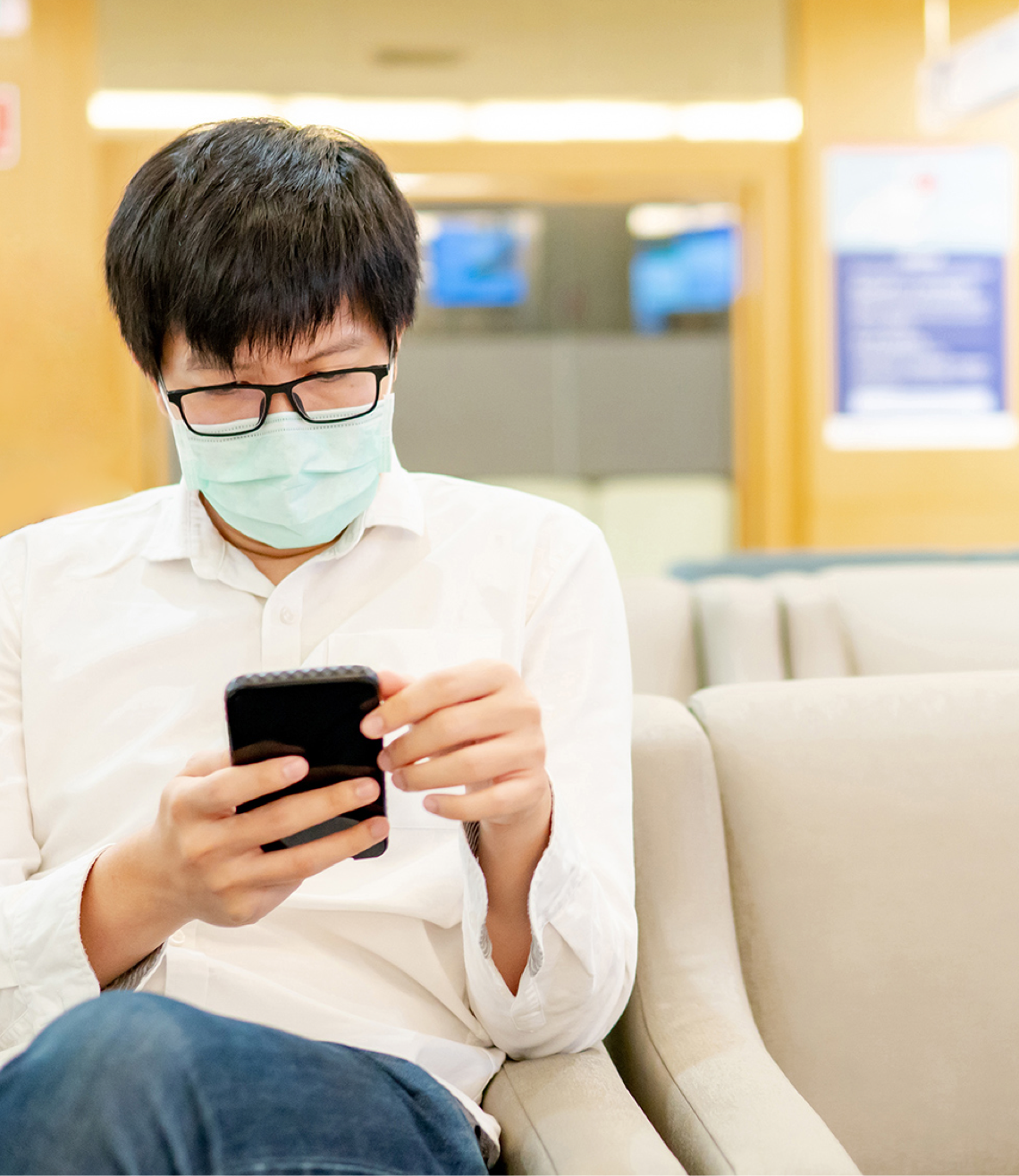 A man is sitting in the waiting area with a phone in his hand.