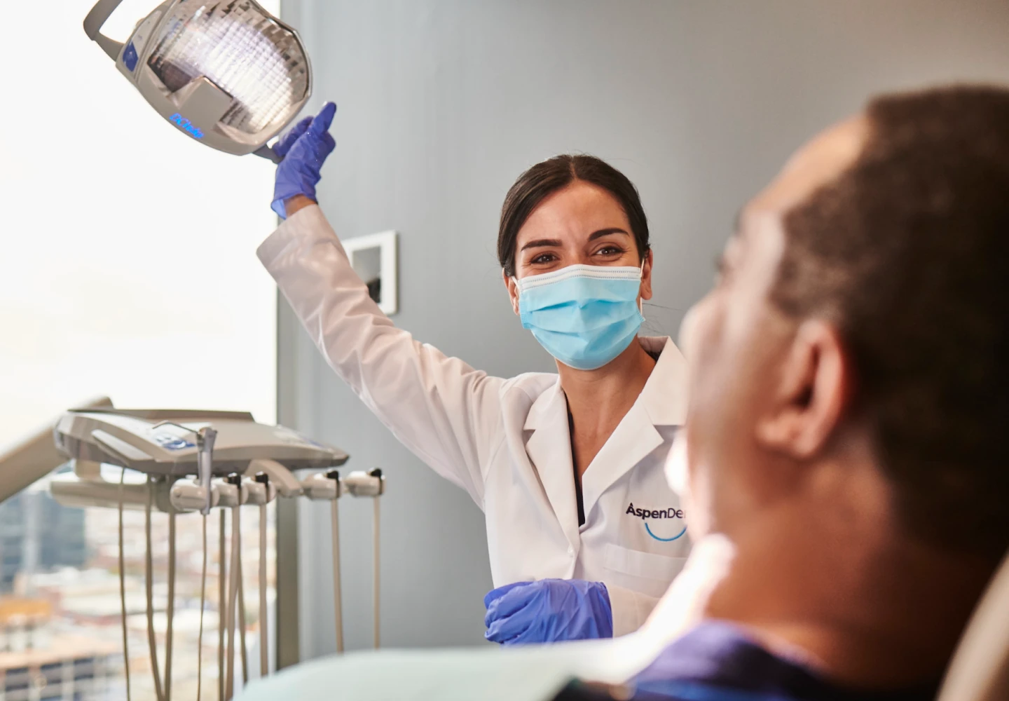 An Aspen Dental doctor moves a light to begin a dental examination. 