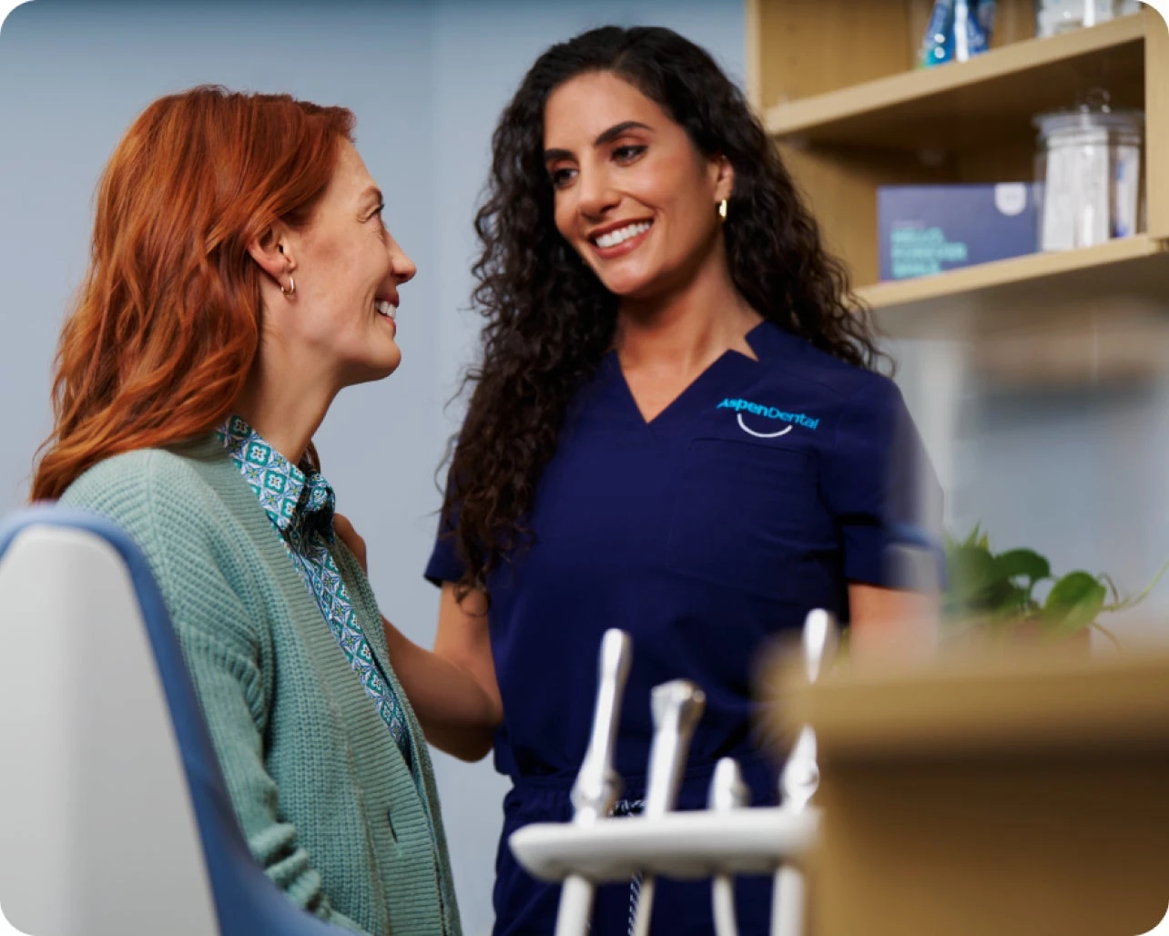 Aspen Dental professional smiling and conversing with a patient during a consultation.