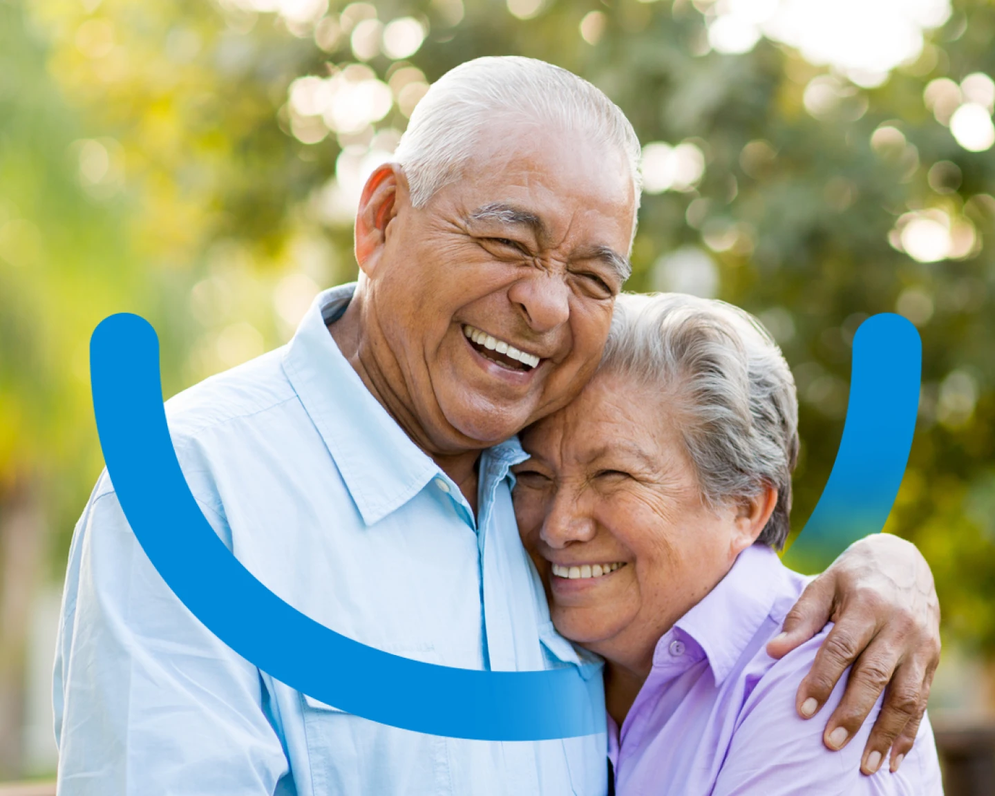 Two elderly people share a joyful embrace outdoors, smiling widely. The image is overlaid with a partial blue smile graphic.
